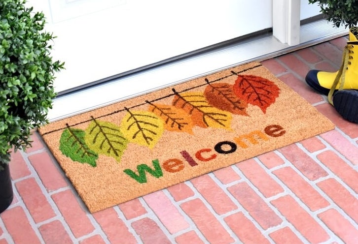 coir welcome mat with different colored leaves printed on it