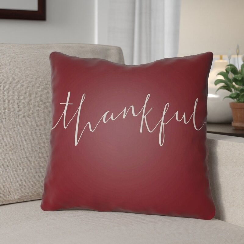 red throw pillow with the word &quot;thankful&quot; in script