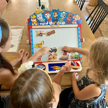 reviewer's children sticking puppy and vehicle wooden magnets on the easel