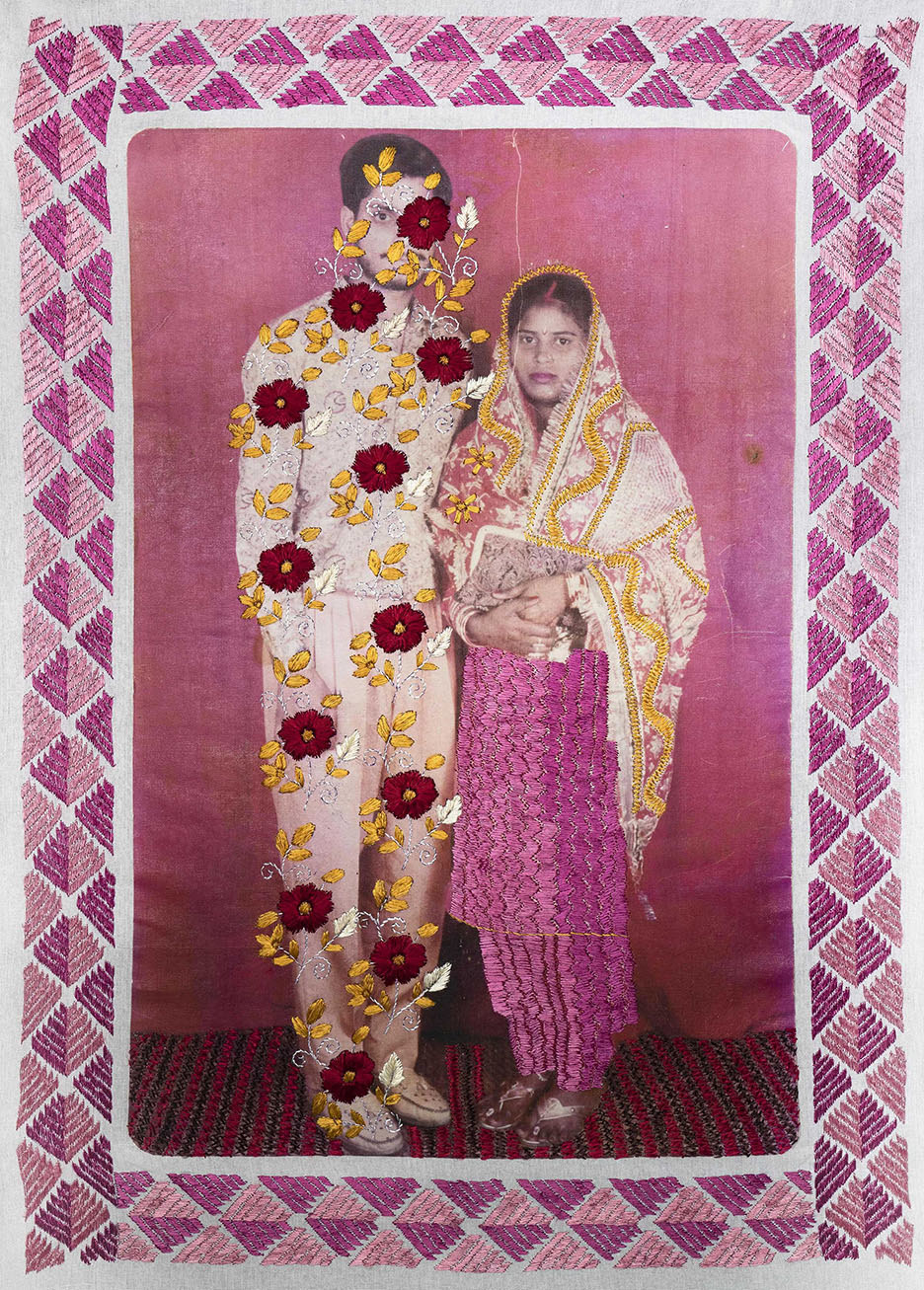 A woman stands next to a man who is covered by embroidered flowers