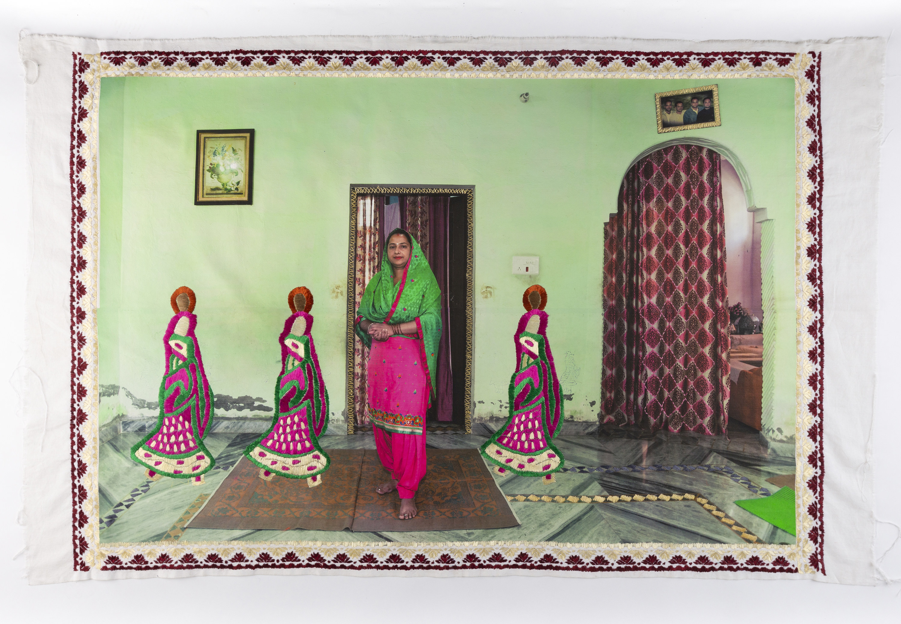 A woman stands in a room with two doorways, next to her three small figures are embroidered 