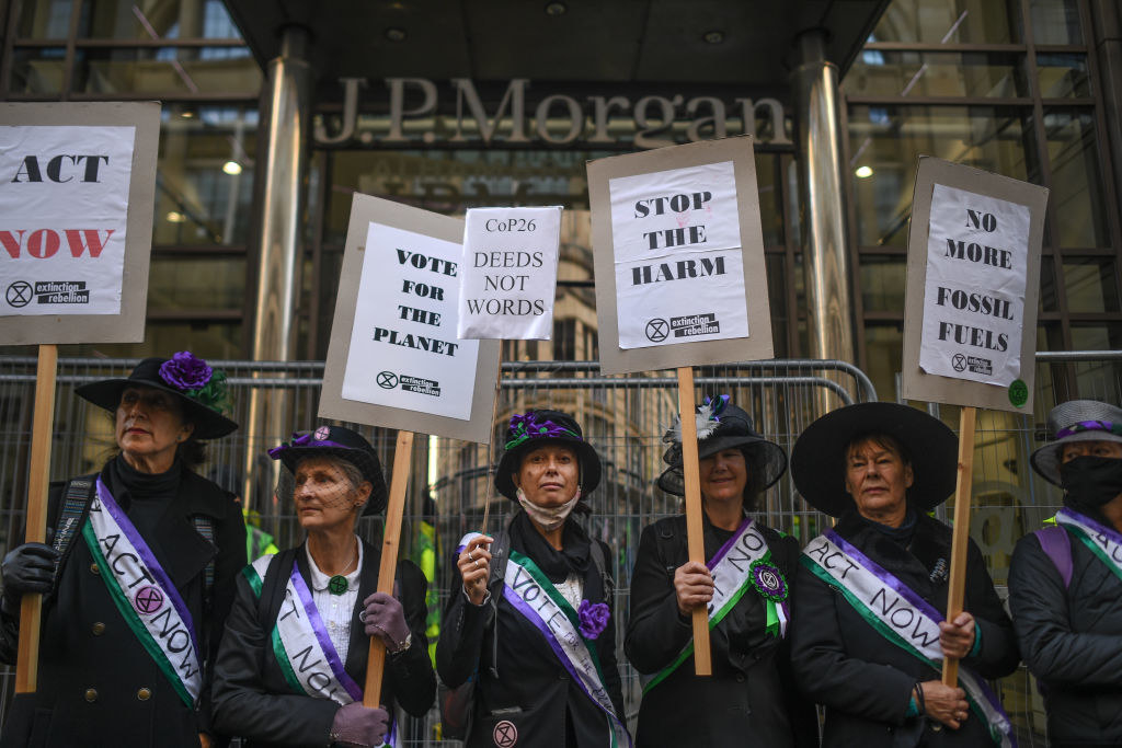 Protesters holding signs that say &quot;Vote For The Planet&quot; and &quot;No More Fossil Fuels&quot;