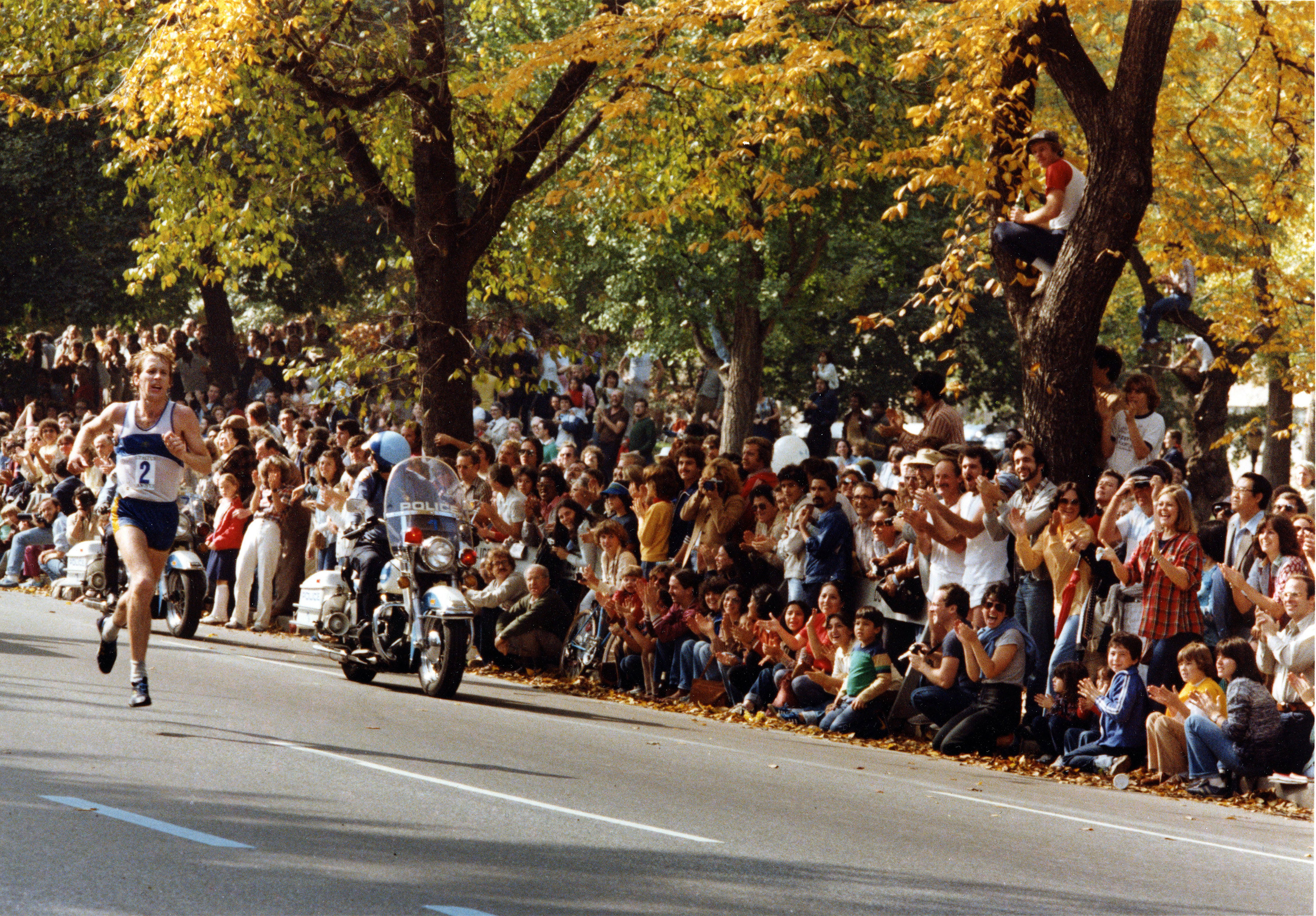 A crowd of spectators beside the road watch Rodgers run