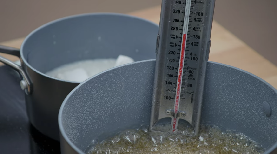 The caramel boiling with candy thermometer inserting