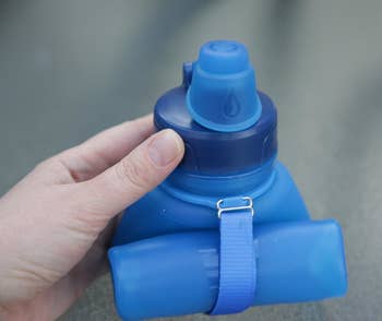 Reviewer holding the rolled up blue water bottle