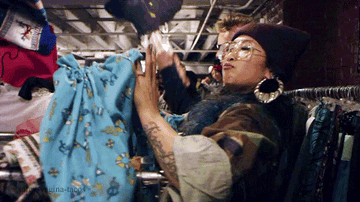Woman holding up clothing in a thrift shop in the Thrift Shop music video