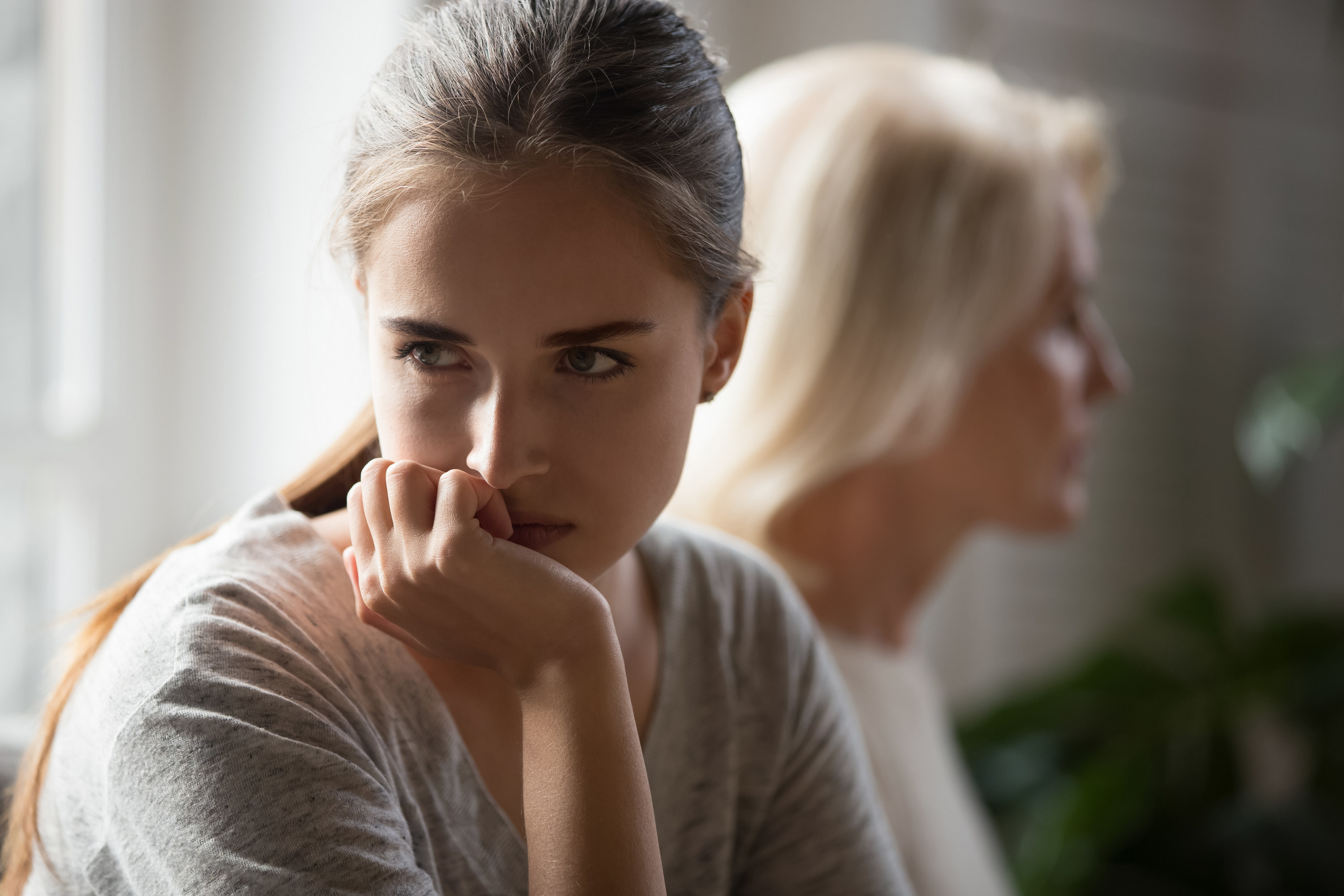 A girl looking off into the distance angrily with a woman sitting next to her