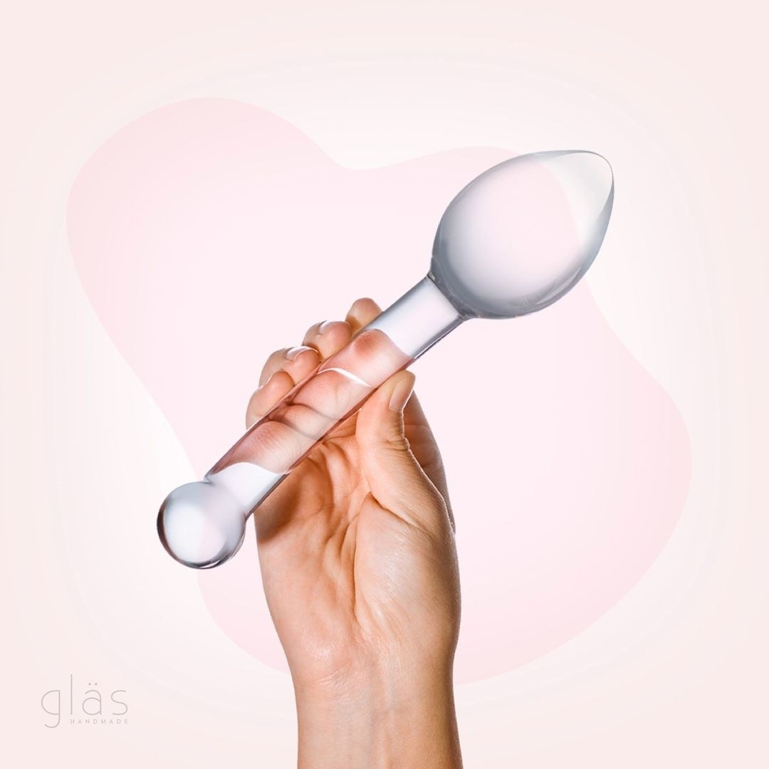 Hand holding transparent glass dildo with large bulb