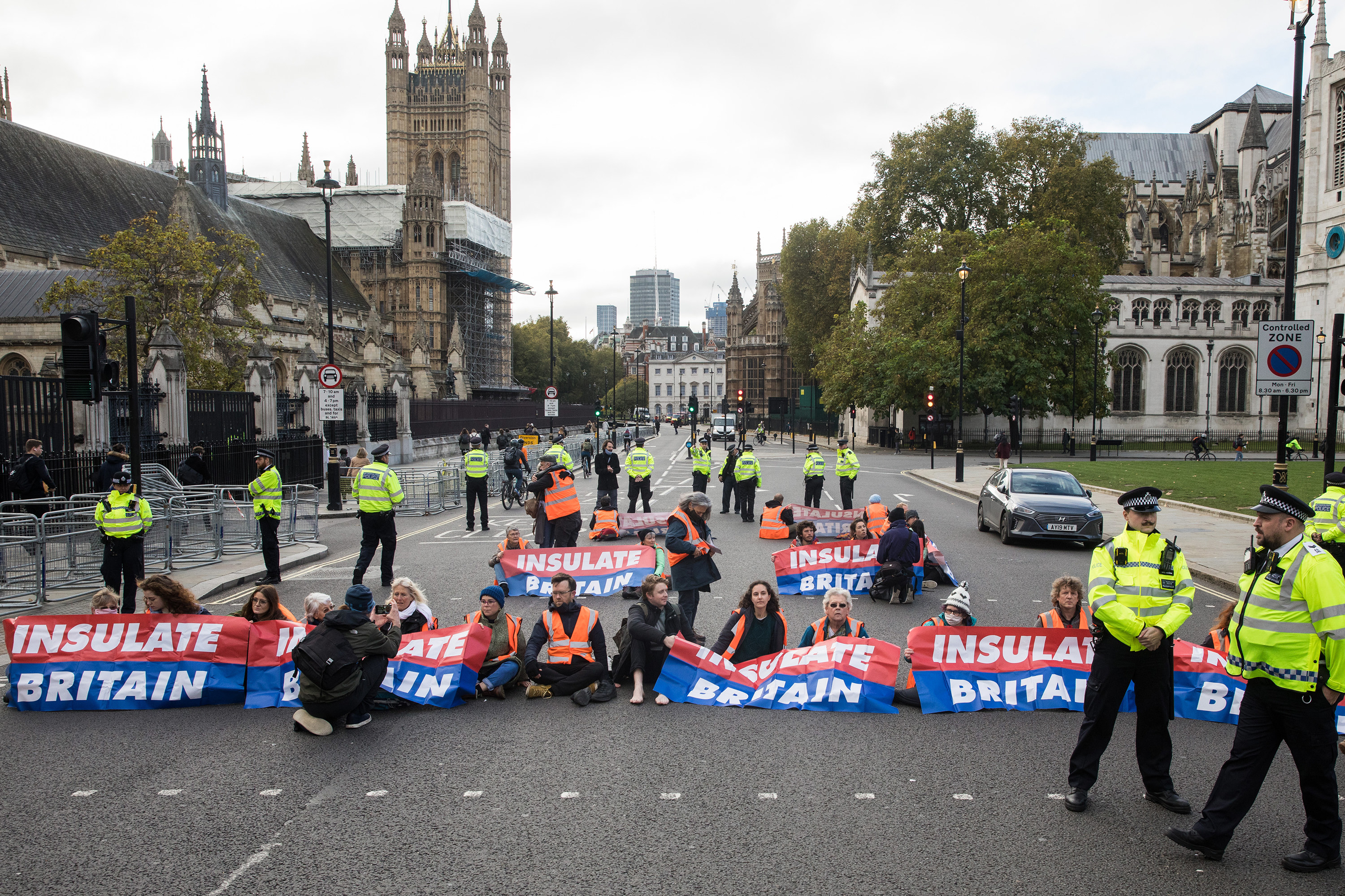 People sit in the middle of a street and hold up banners that read &quot;insulate Britain&quot;