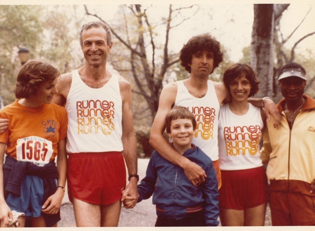 Two smiling runners hug and hold hands of children and other family members