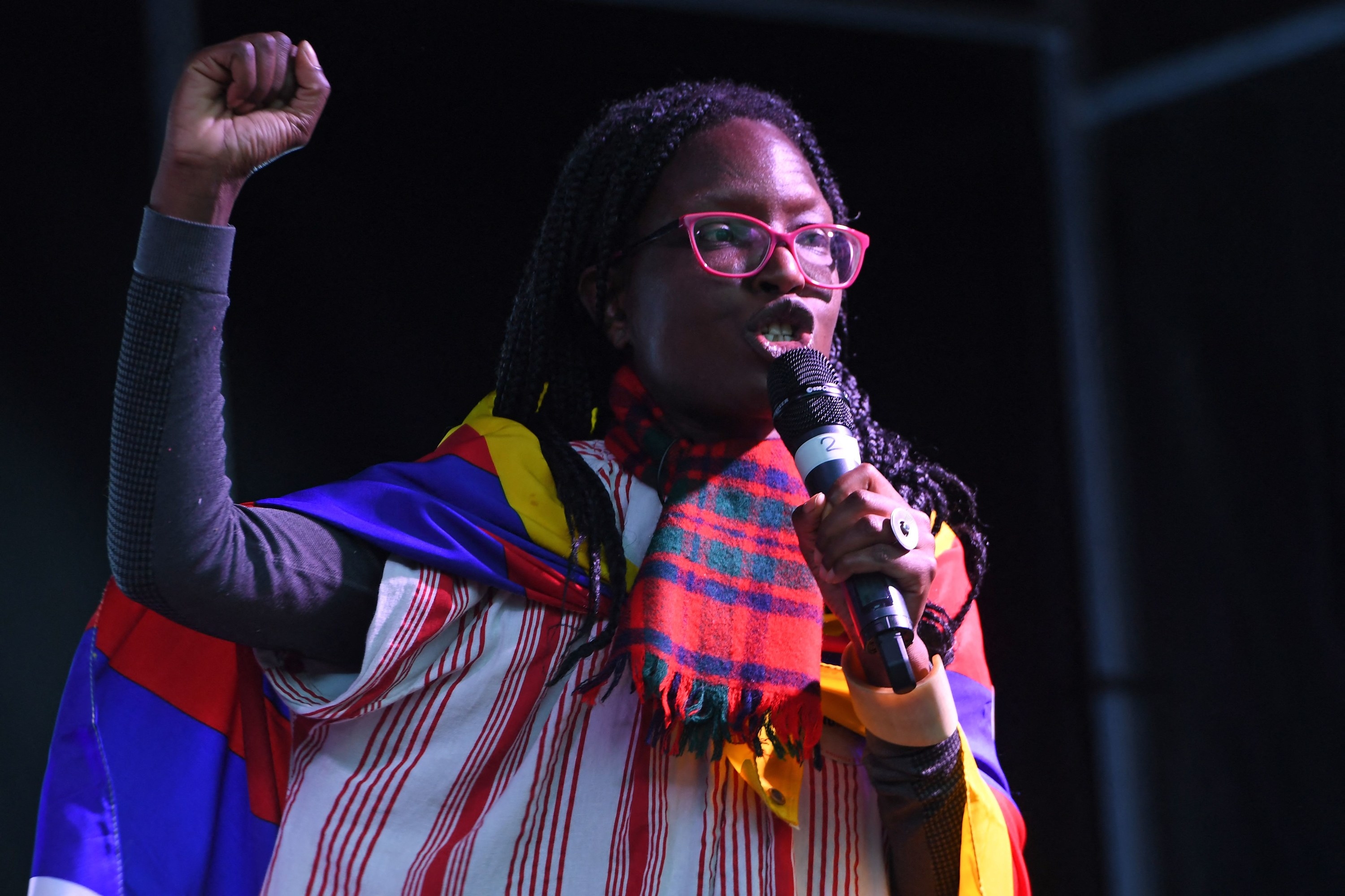 A person speaks into a microphone and holds up a fist