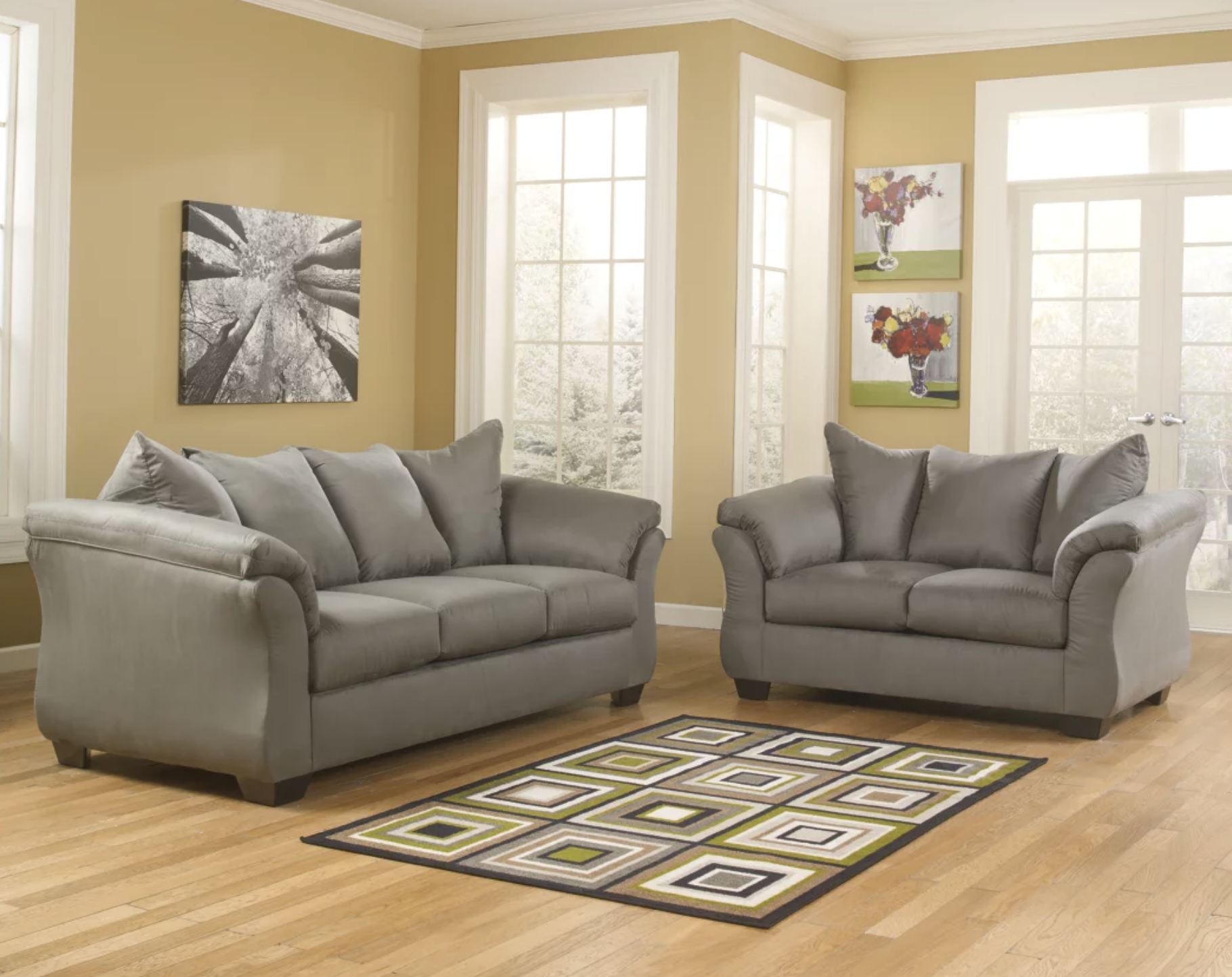 Two gray polyester couches around a rug with green, white, and brown squares