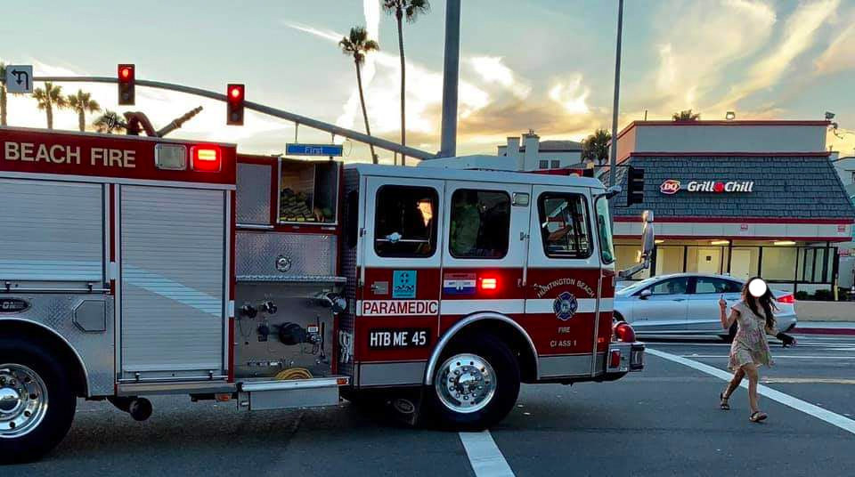 A person in a crosswalk flashes a middle finger at a paramedic vehicle trying to drive by