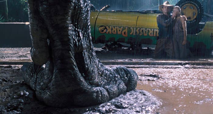 A tyrannosaurus rex foot, standing in the mud as Dr. Grant and Lex stand still