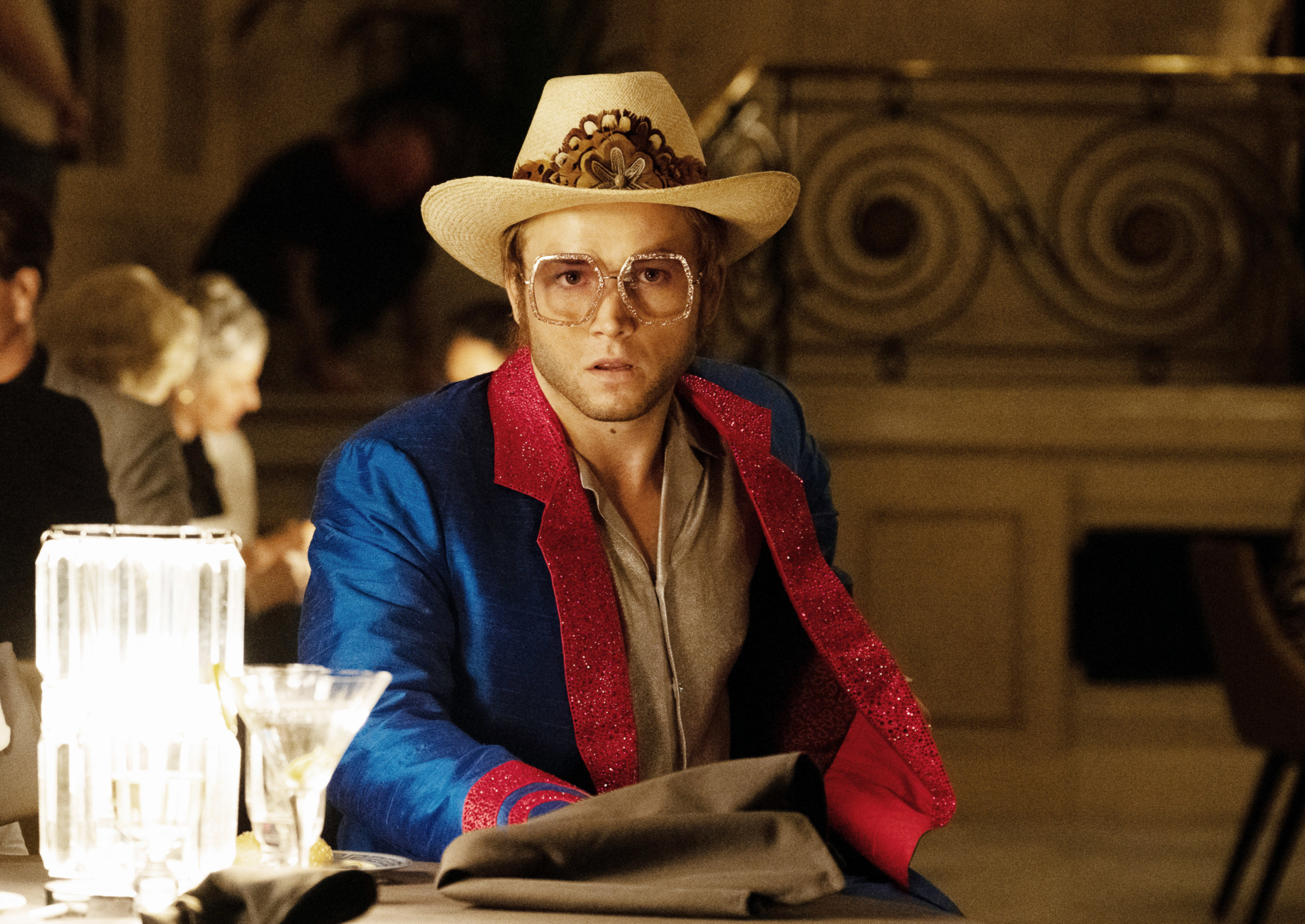 Taron Egerton as Elton John sitting at a bar