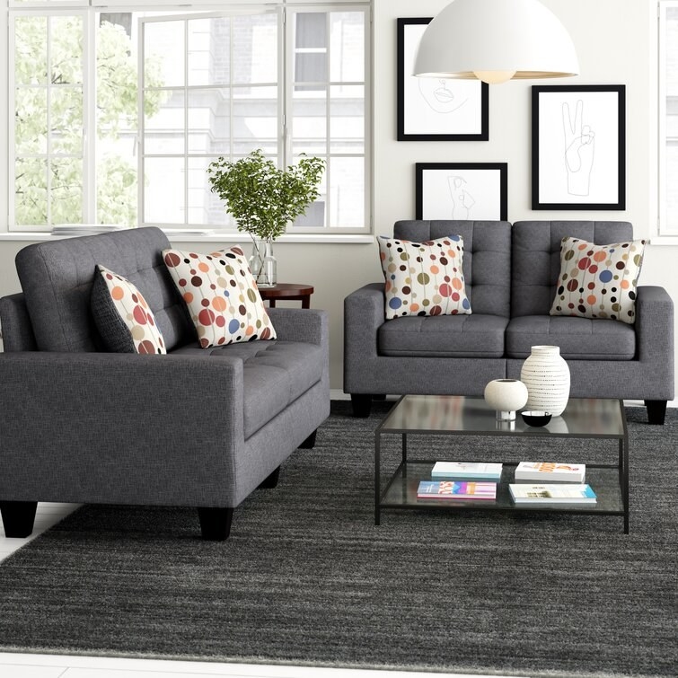 Two gray couches around dark gray rug and glass coffee table