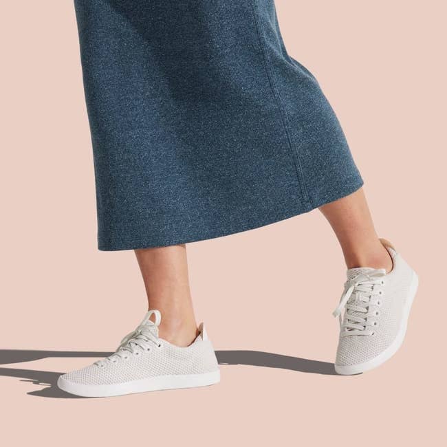 Model wearing the white sneakers with a dark gray midi skirt