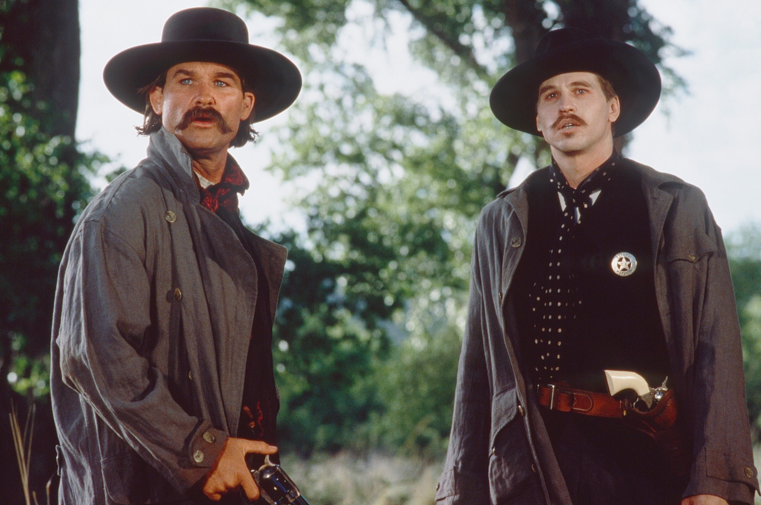 Wyatt Earp and Doc Holiday looking concerned, standing in a field