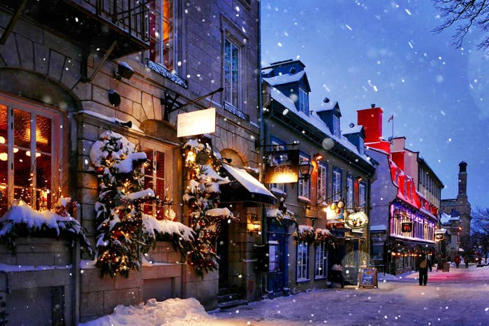 Snowy scene with a small town street lined with lights and holiday decorations