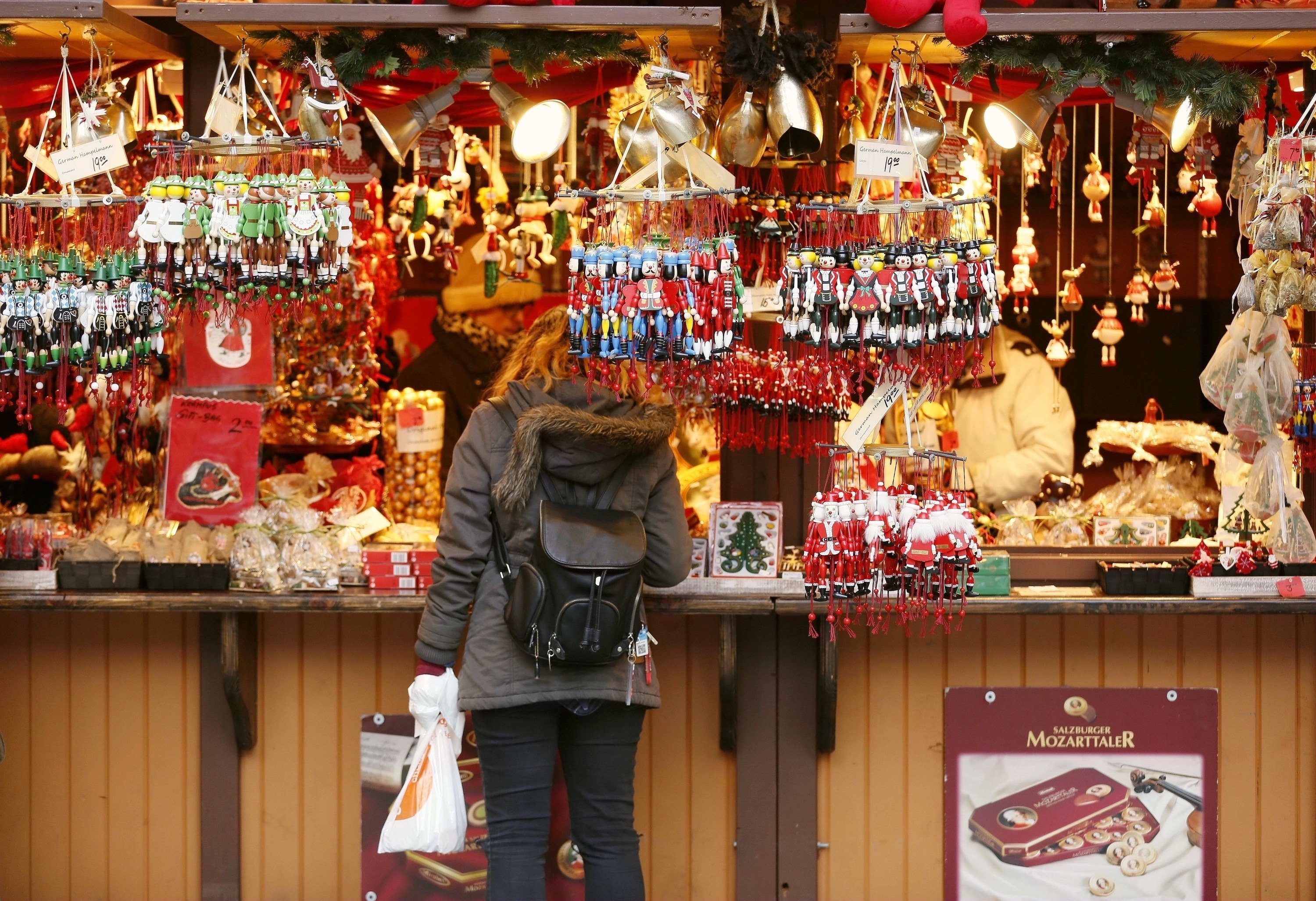 Person standing at a counter with all kinds of Christmas decorations hanging