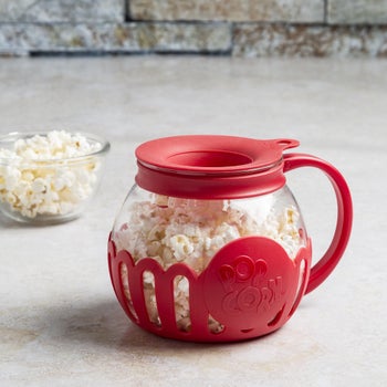 the same glass container, which looks like a coffee pot, filled with popped popcorn