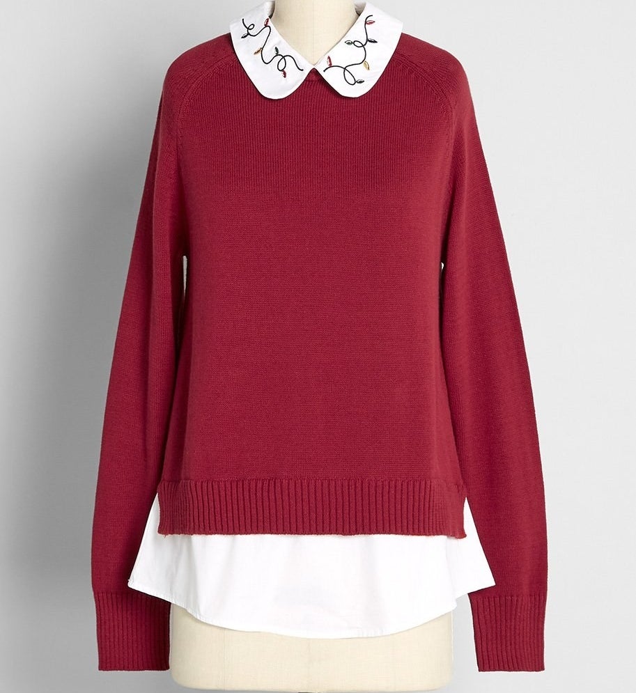 A ruby red sweater-shirt combo with a white collar that has embroidered string lights on it