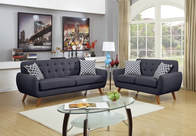 Two gray couches around a white rug and glass coffee table