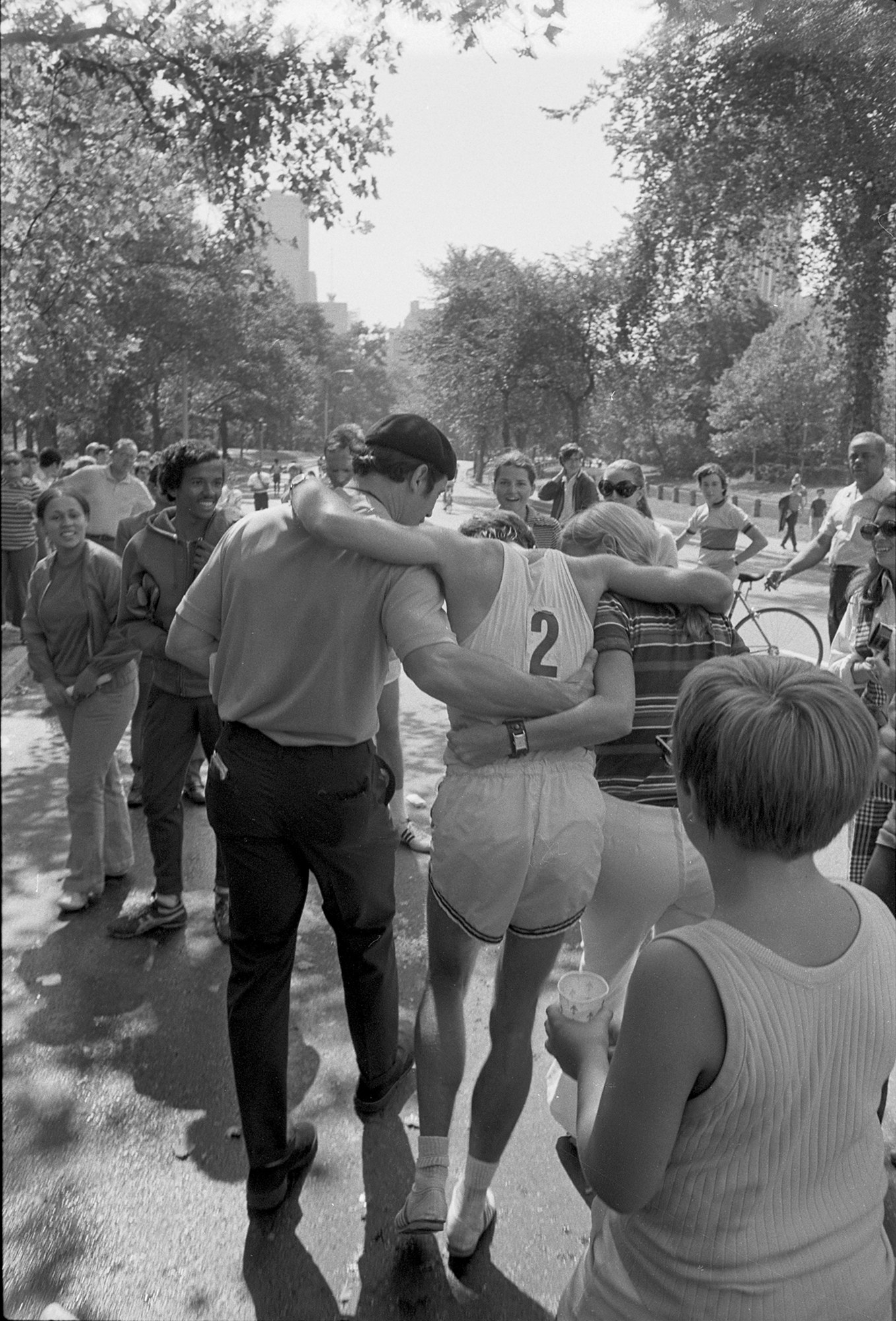 Two people support Muhrcke after finishing the race as spectators look on