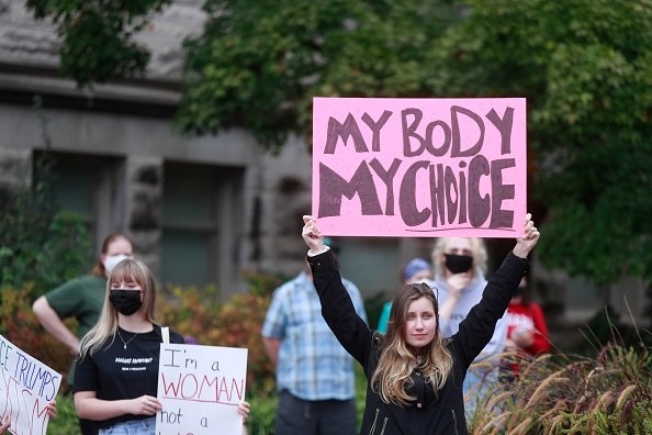 A woman holding up a sign that reads, &quot;my body, my choice&quot;