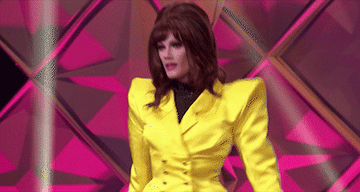 drag queen wearing an 80&#x27;s power suit with huge shoulder pants on the runway