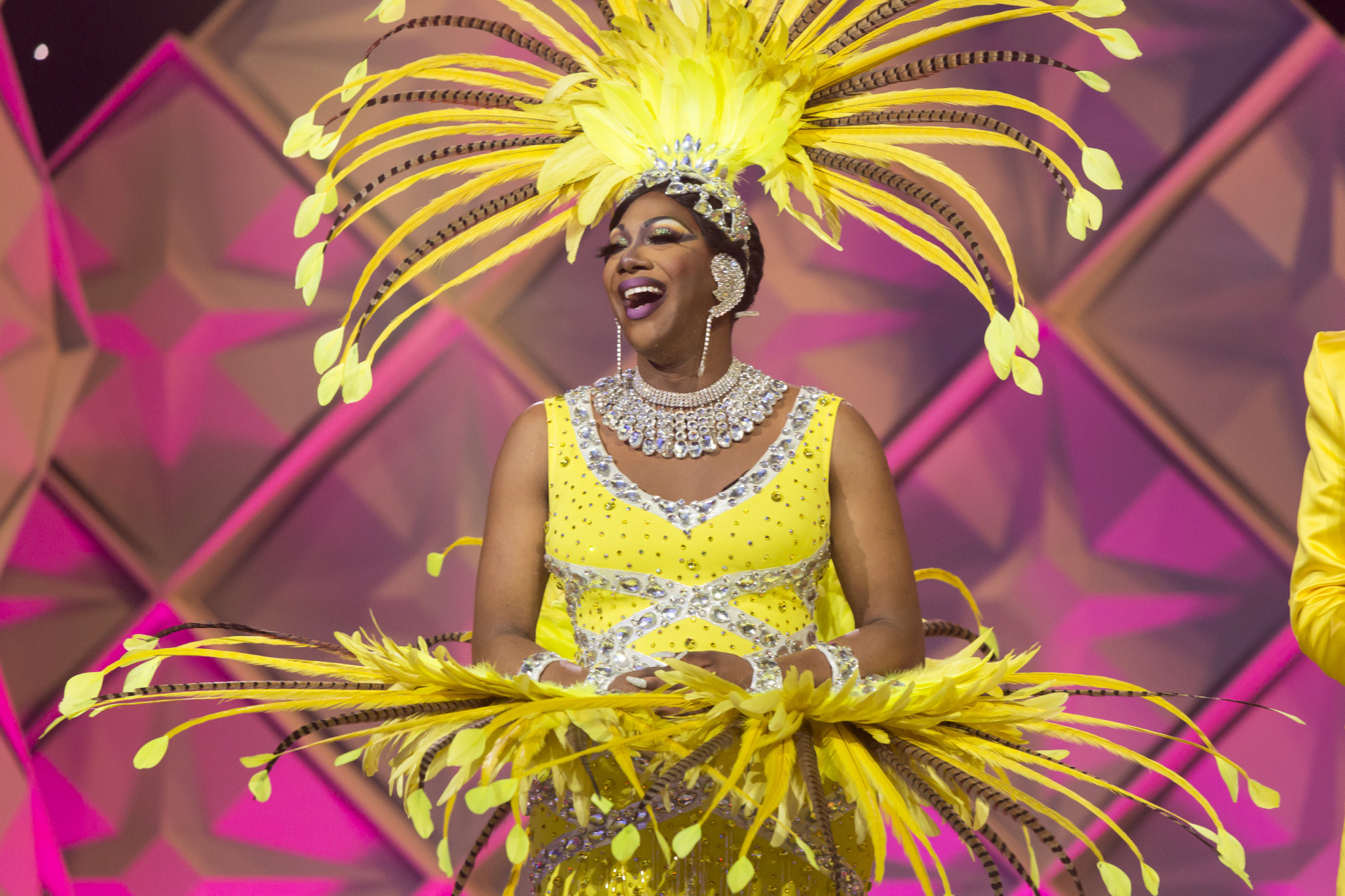 Drag queen with beautiful yellow outfit on with giant yellow feathers as a head piece