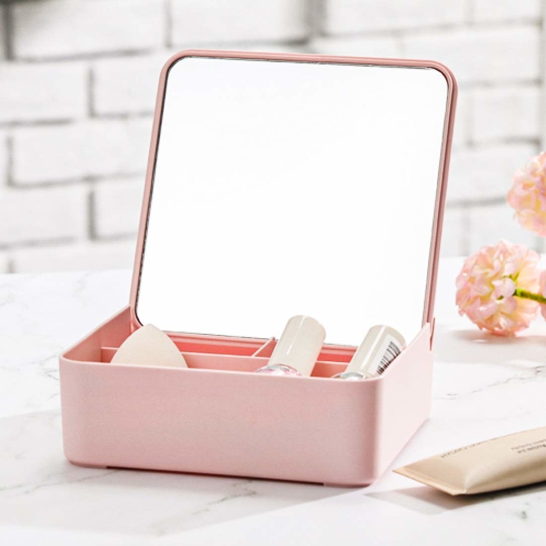 A pink mirror with makeup products in the storage compartment
