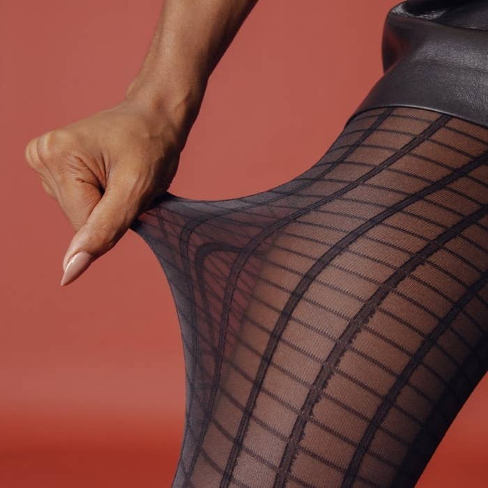 A person pulling on the side of a pair of gridded tights