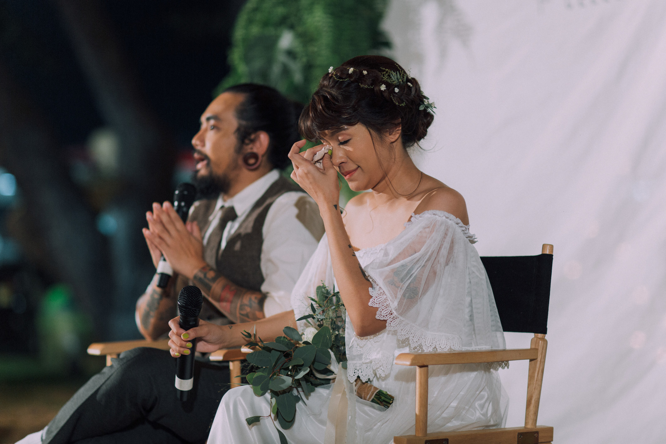 A bride wiping away tears as they sit next their groom