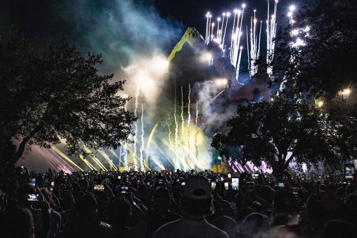 Dramatic stage lights at outdoor festival as crowd watches