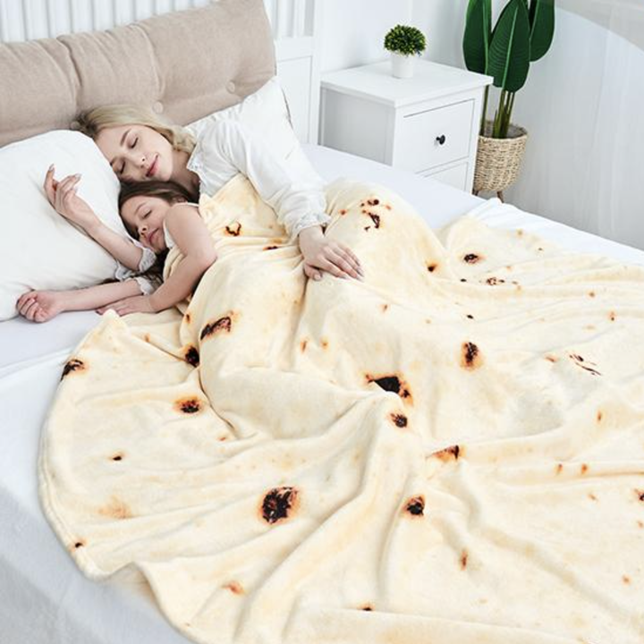 two models lay in bed with the burrito blanket wrapped around them