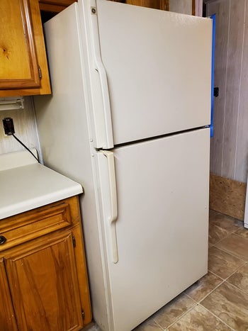 on left, white fridge next to wooden cabinet