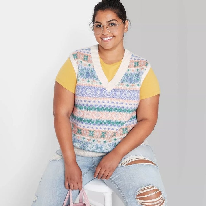 A model wearing a purple/green/orange/white sweater vest