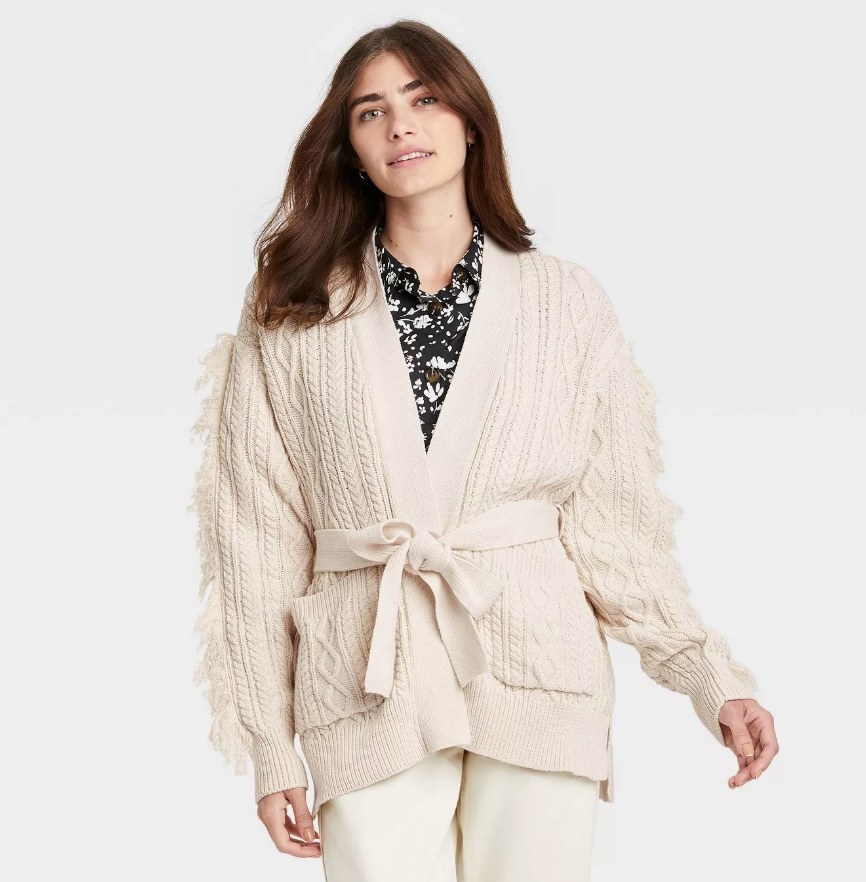 A model wearing a cream belted cardigan