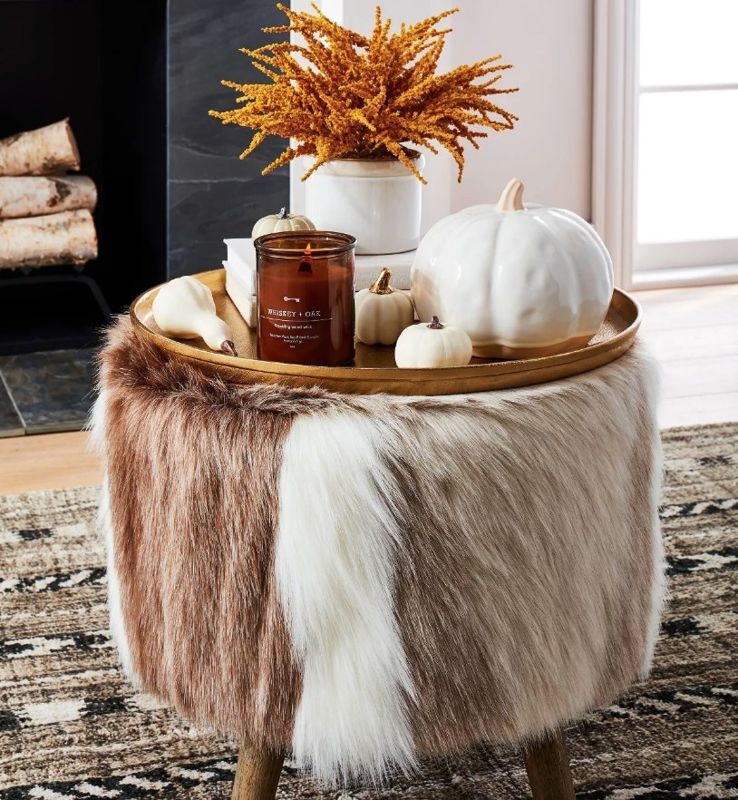 A brown/white faux fur ottoman with a tray table atop