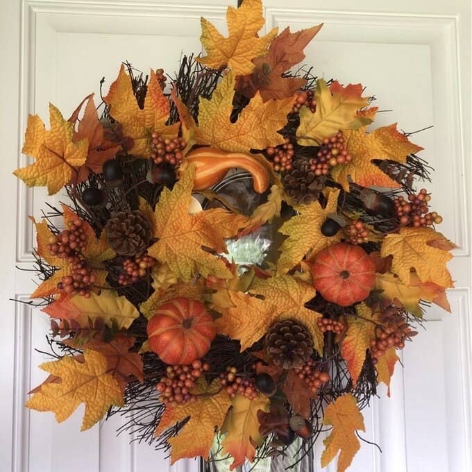reviewer photo of orange and yellow wreath with pumpkins and maple leaves, on a door