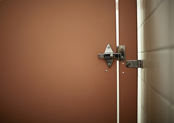 A close-up of a slit in a bathroom stall door
