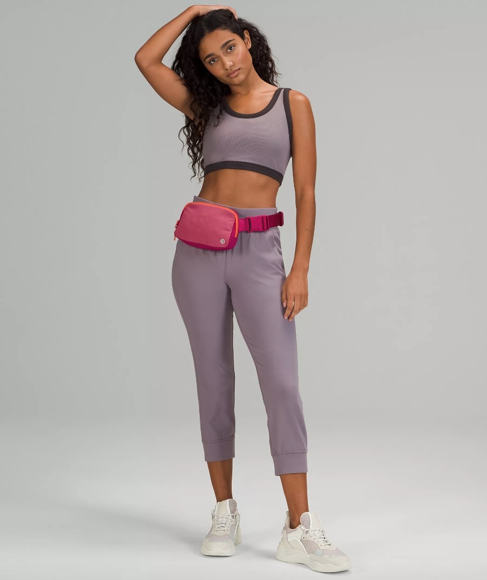 Model wearing pink belt bag with purple outfit