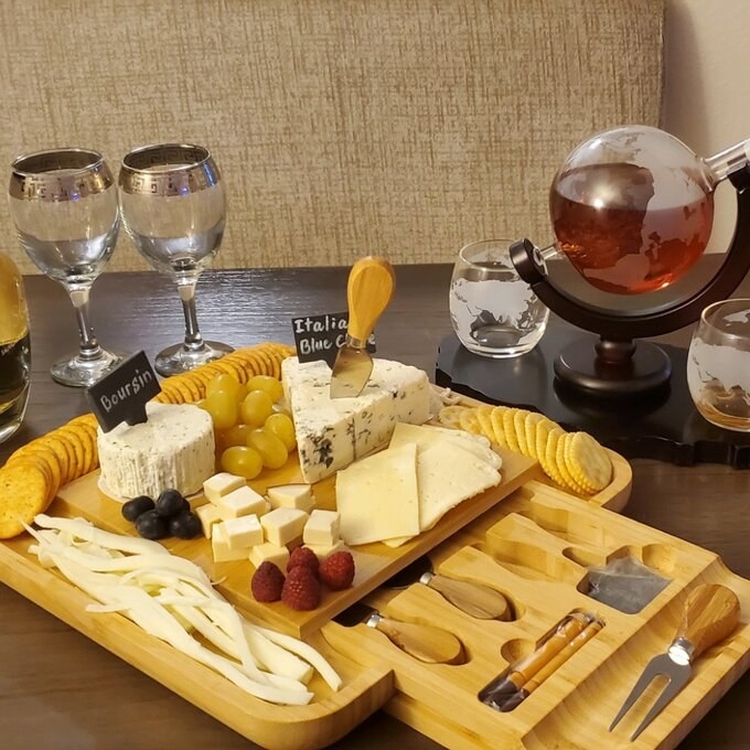 reviewer photo of cheeseboard with cheeses and crackers on top, and the drawer with cheese knives pulled out