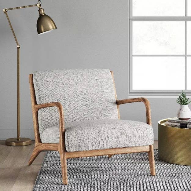 a grey upholstered arm chair with wooden arms and legs