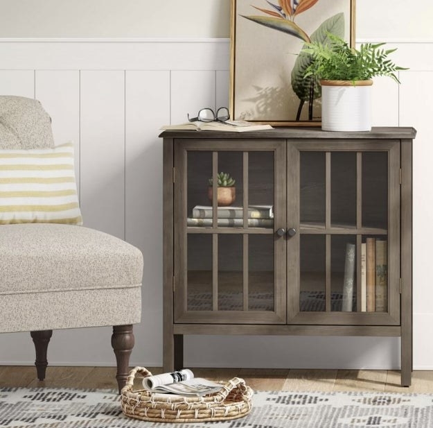 a brown accent cabinet with two shelves inside and glass doors