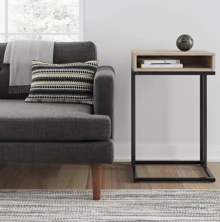 The black and oak colored table has a clean still frame and a small open drawer
