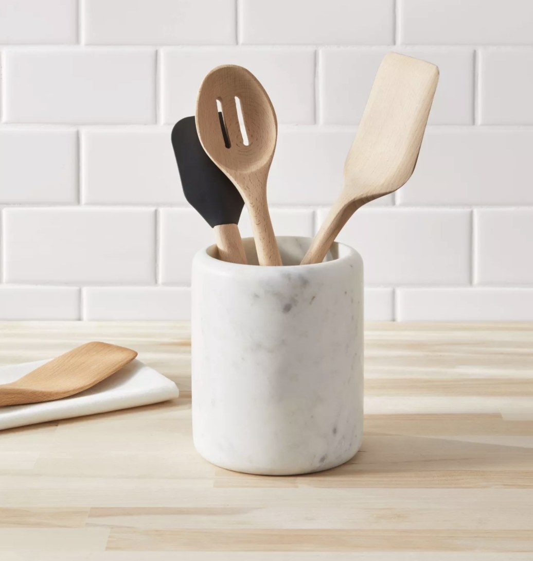 The grey and white marble utensil holder has wooden tools inside