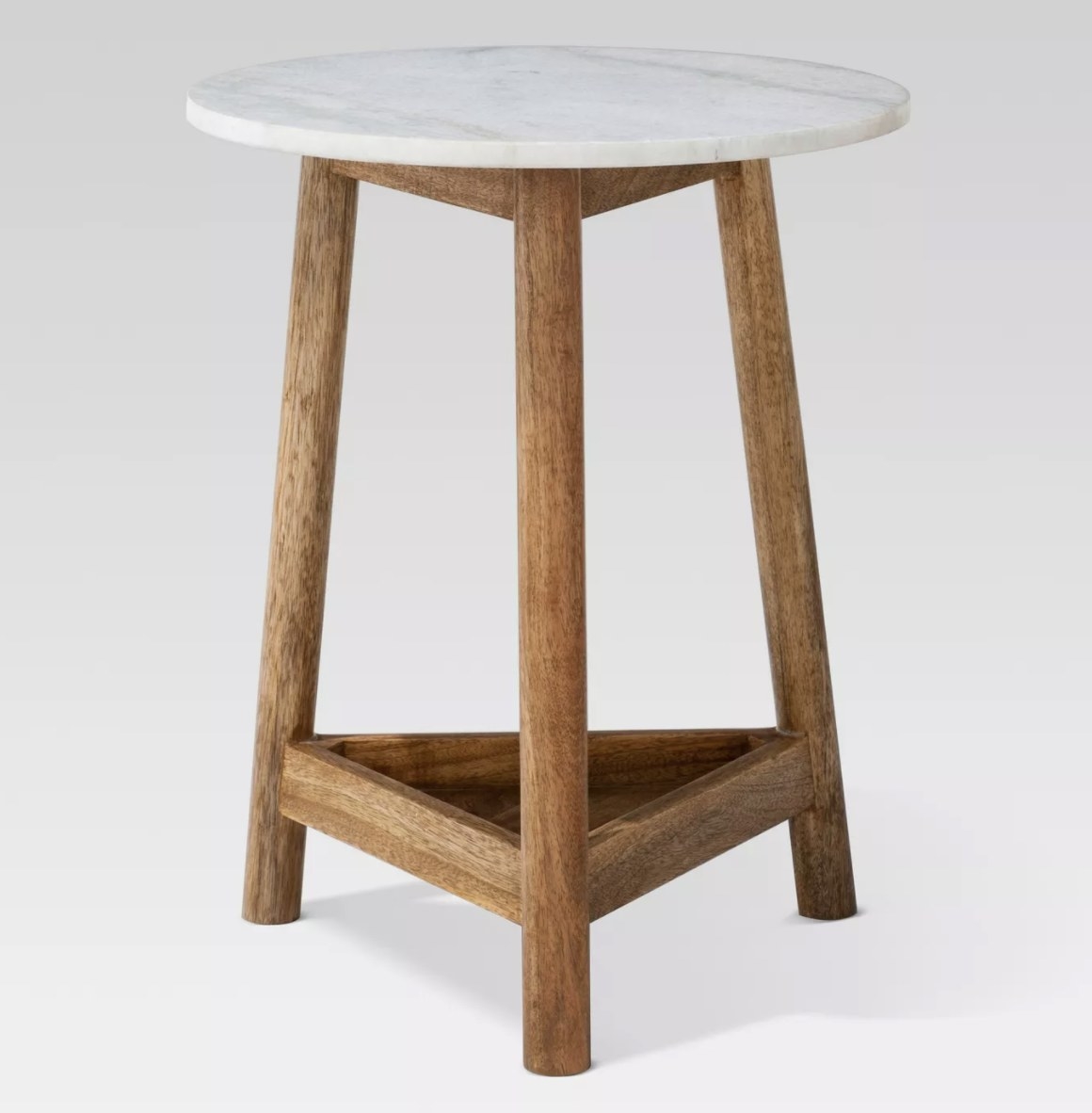 The table has three light brown wooden legs, a triangular shelf base and a circular top of white marble