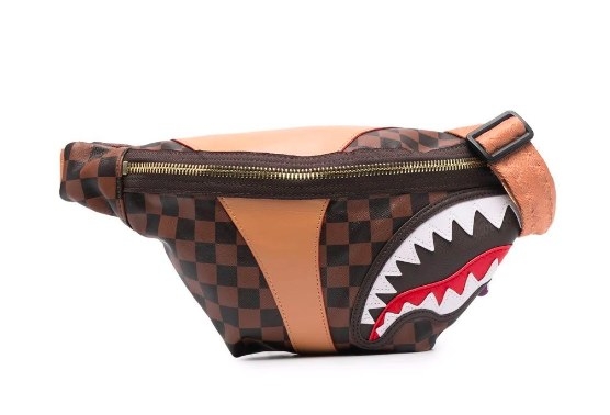 The belt bag with brown checker print, a shark mouth logo on the corner, and gold zipper